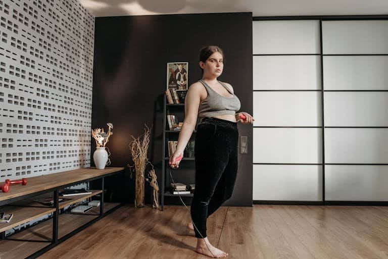 A woman performs a jump rope workout at home, focusing on fitness and health.