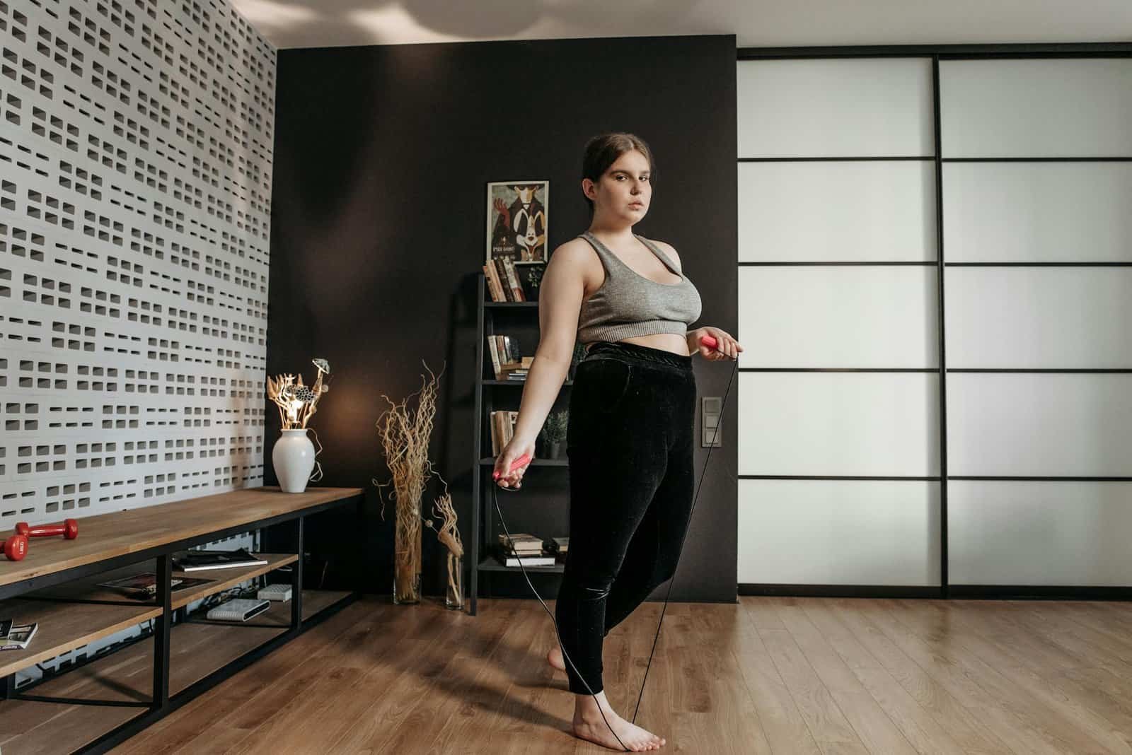 A woman performs a jump rope workout at home, focusing on fitness and health.