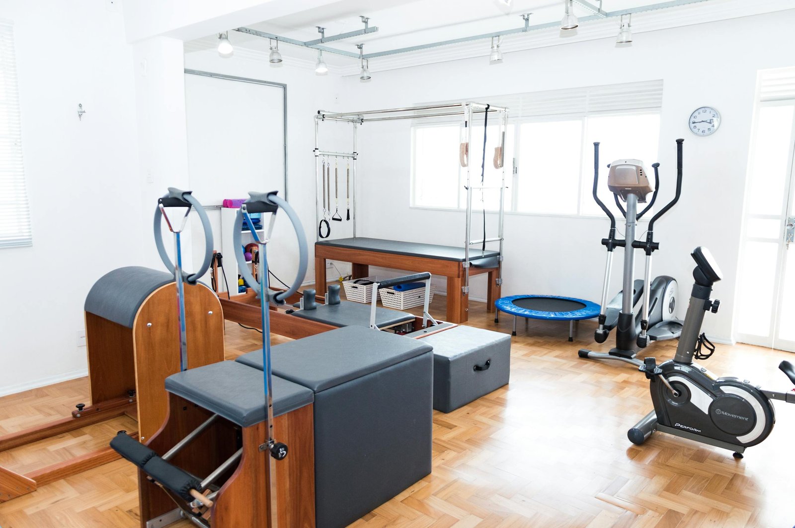 Bright gym space featuring Pilates equipment, exercise bikes, and wooden flooring for a modern workout experience.