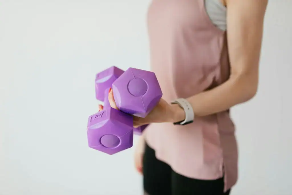Woman holding compact hex dumbbells for a small bedroom home gym setup