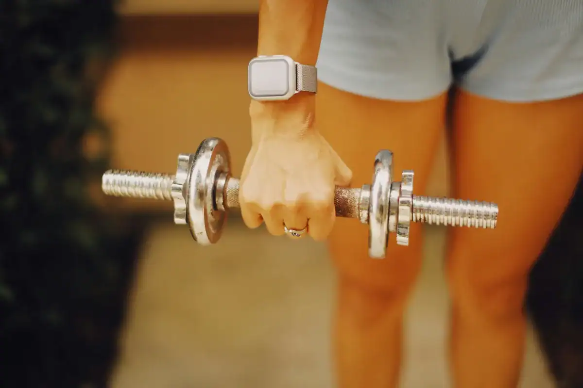 Close-up of hand gripping an adjustable dumbbell handle with an apple watch on the wrist