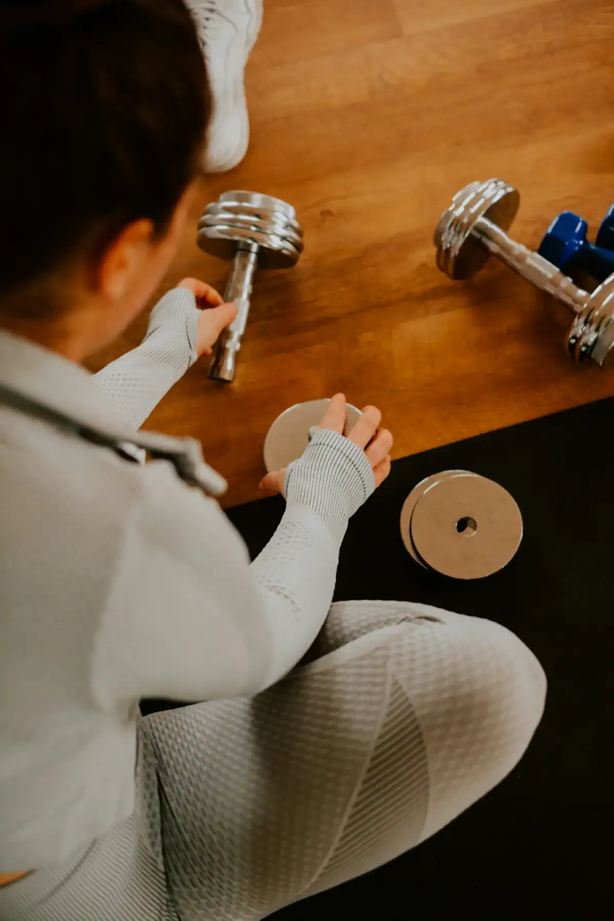 Woman adjusting screw collar plates on a pair of adjustable dumbbells